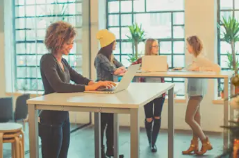 Women using standing desks in an office.