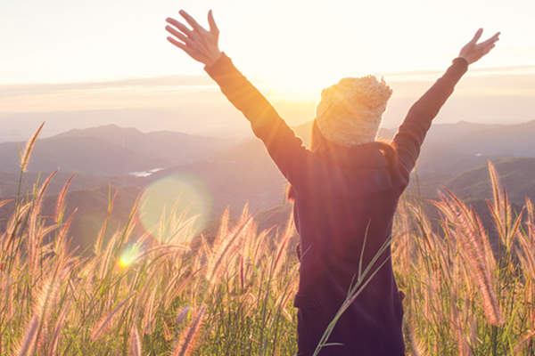 女人养双臂在阳光明媚的领域。