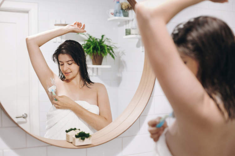 年轻女子在白色的毛巾剃腋毛带淋浴后蛏塑料