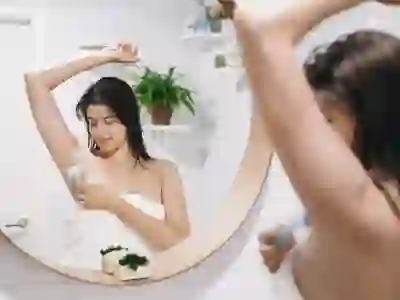年轻女子在洗完澡后用塑料剃须刀刮腋窝