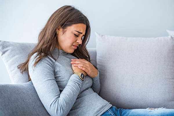 年轻女子与胃灼热坐在沙发上。