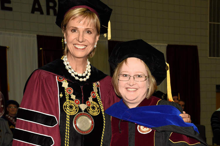 朱莉(右)从德州女子大学校长Carine Feyten那里获得博士学位。