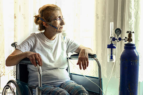 高级妇女戴着氧气罩。