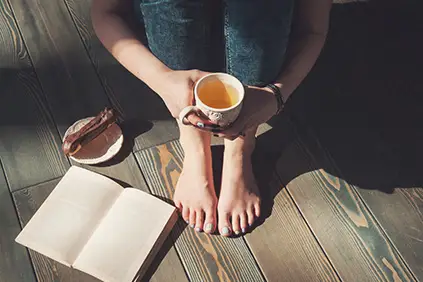 一个女人坐在一边喝茶一边看书。