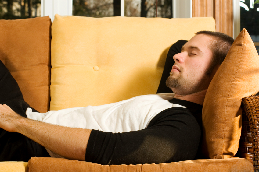 疲乏的年轻人躺在沙发上。