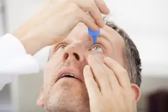 一个干眼症患者正在往眼睛里滴眼药水。