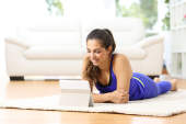 一个女人看着平板电脑，而在地毯上铺设。
