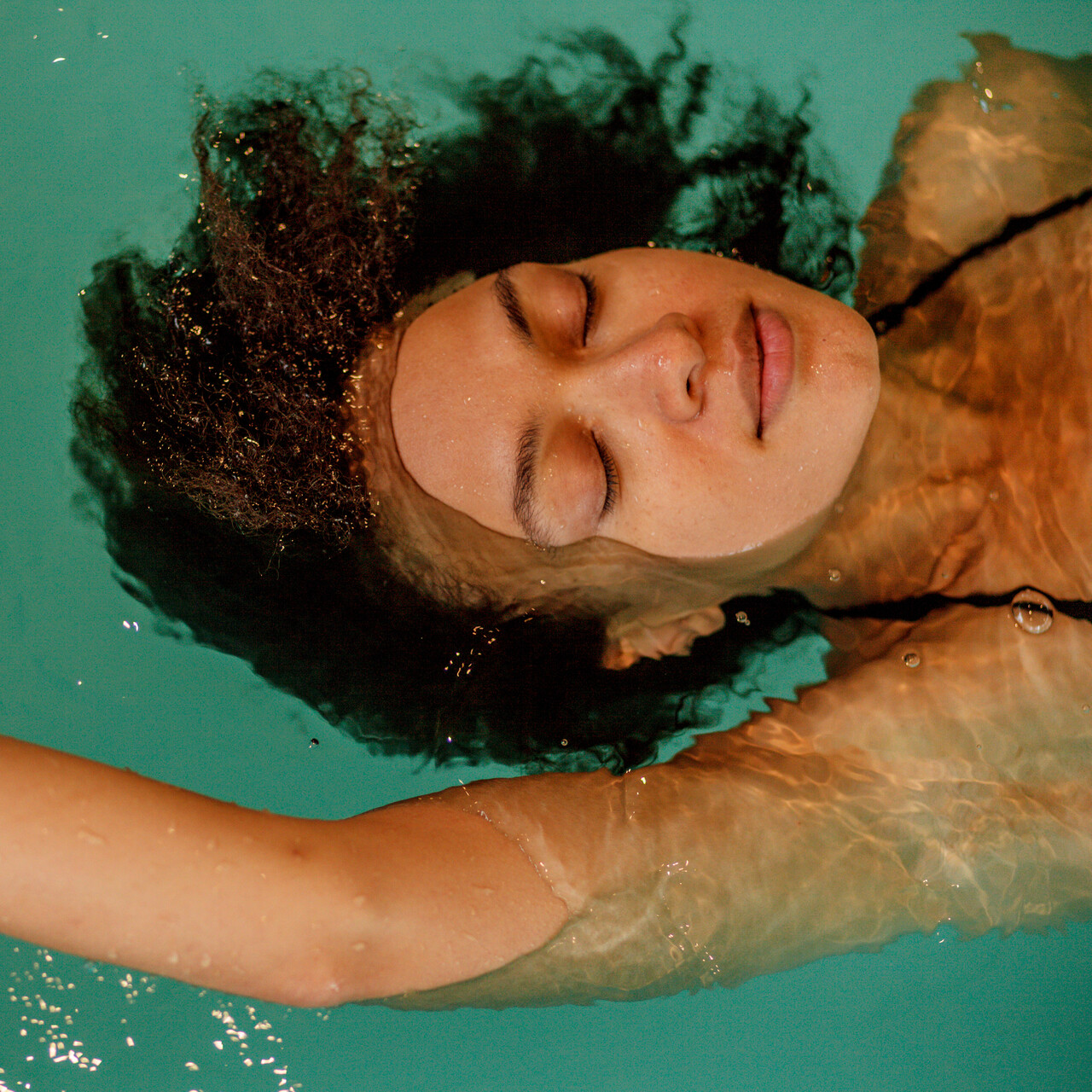 女子放松漂浮在游泳池。