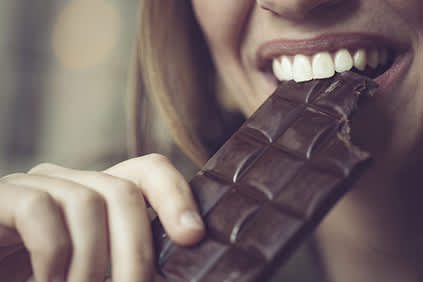 女人吃黑巧克力棒。