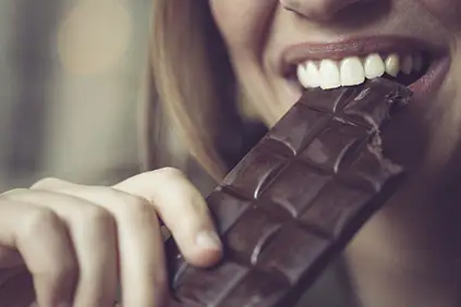 一个女人正在吃一块黑巧克力。