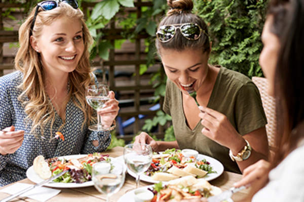 一群朋友吃着沙拉,面带微笑。