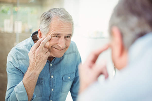 老人检查他在镜子皮肤。