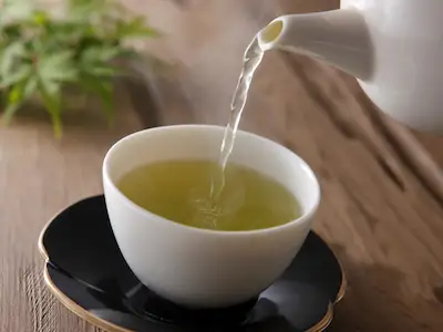 绿茶从茶壶中倒进茶托上的茶杯中。
