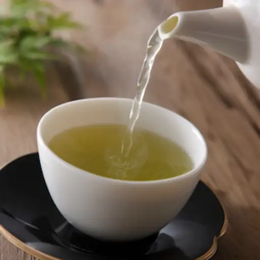 绿茶从茶壶中倒进茶托上的茶杯中。