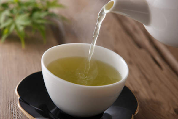 绿茶从茶壶中倒入茶托上的茶杯中。