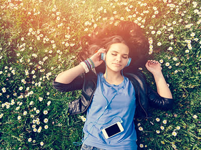 女人在公园的草地上放松，戴着耳机听音乐。