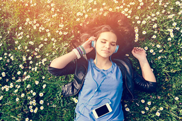 女人在公园的草地上放松,戴着耳机听音乐。