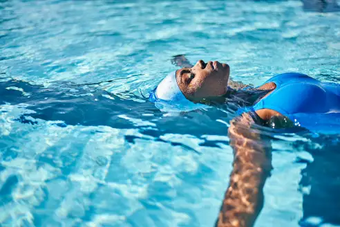 A woman floats on her back in a swimming pool