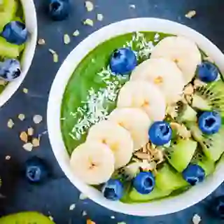 Green smoothie bowl with banana, kiwi, blueberry, granola.