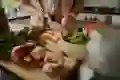 A woman chops vegetables on a cutting board