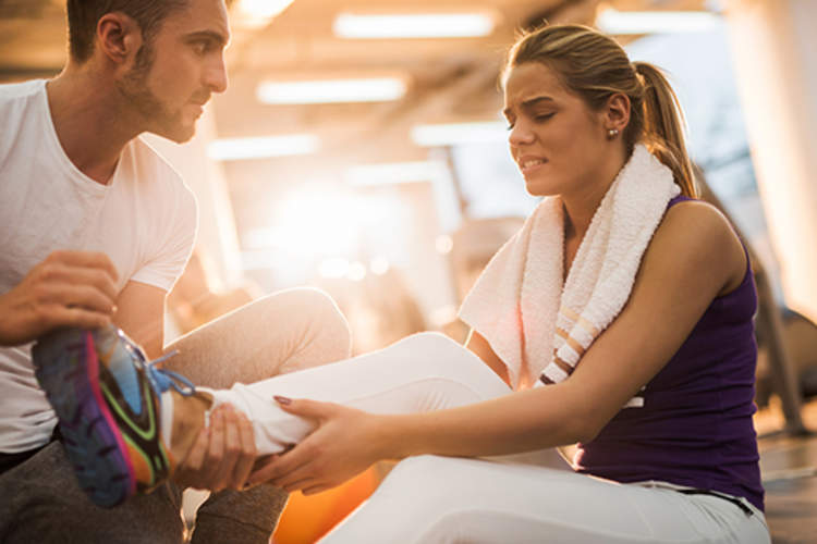 健身教练与脚踝受伤的妇女一起工作。