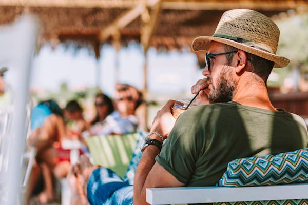 穿棉衬衫戴草帽的男人,喝饮料,度假