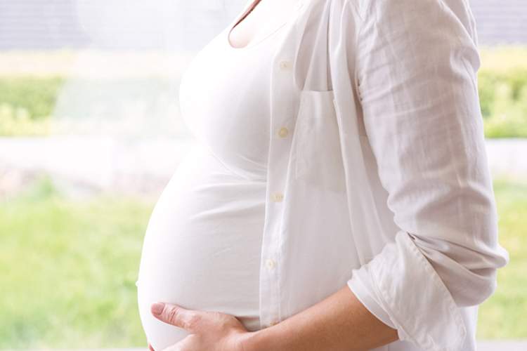 站在窗户前的孕妇。