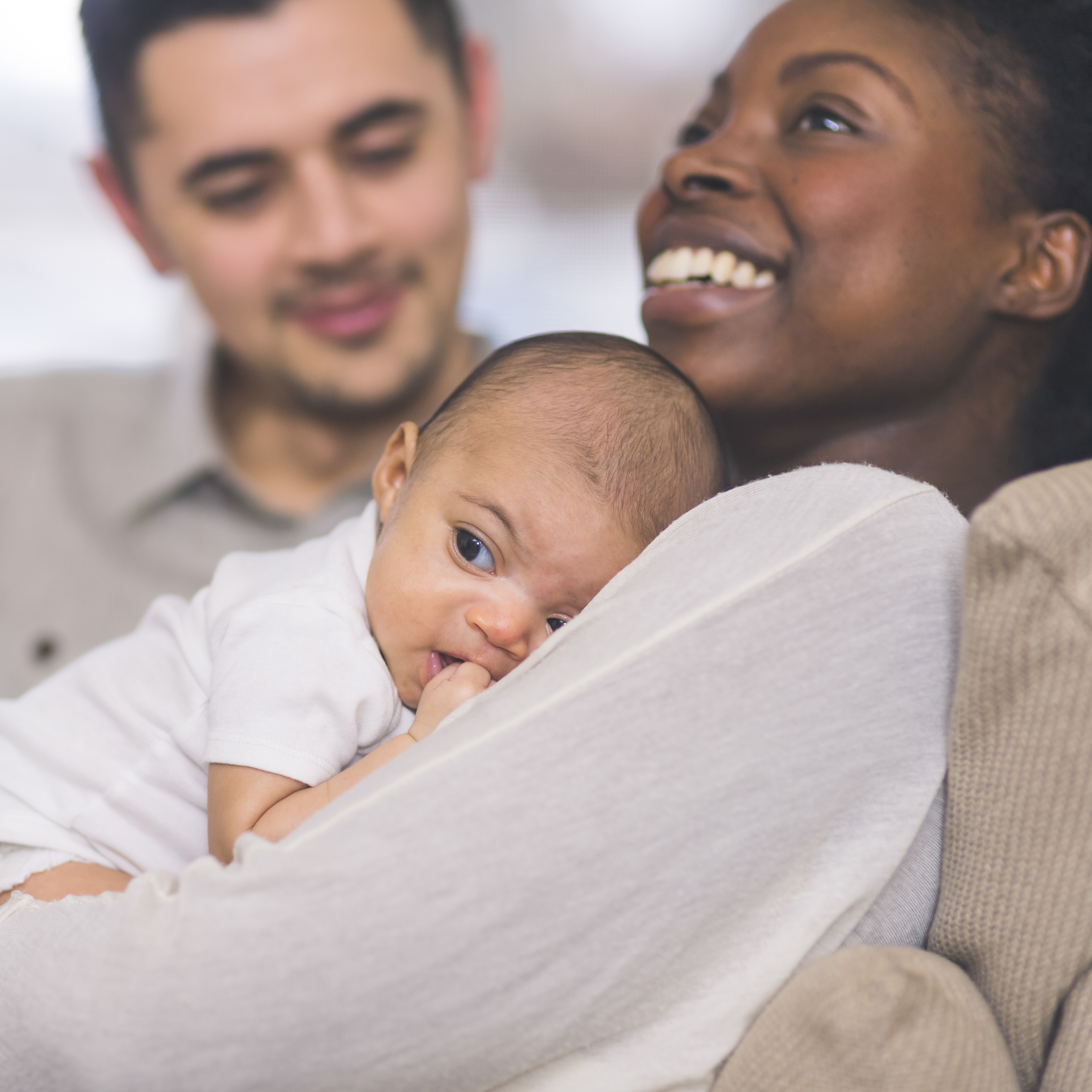 一对夫妇和他们的小女儿依偎在家里的沙发上。