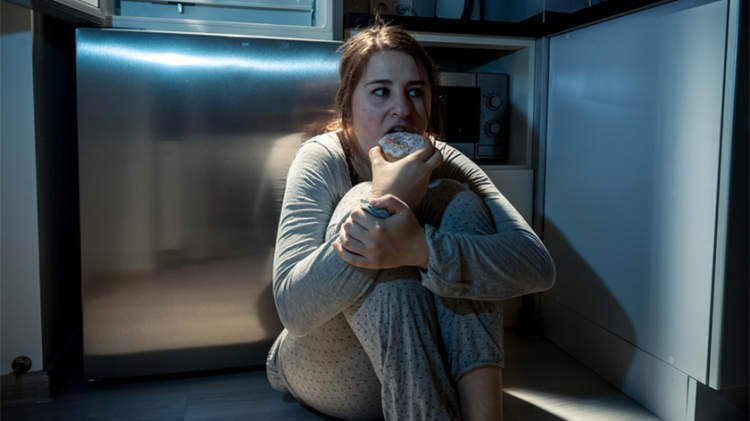 女子坐在厨房的地板上，晚上吃。