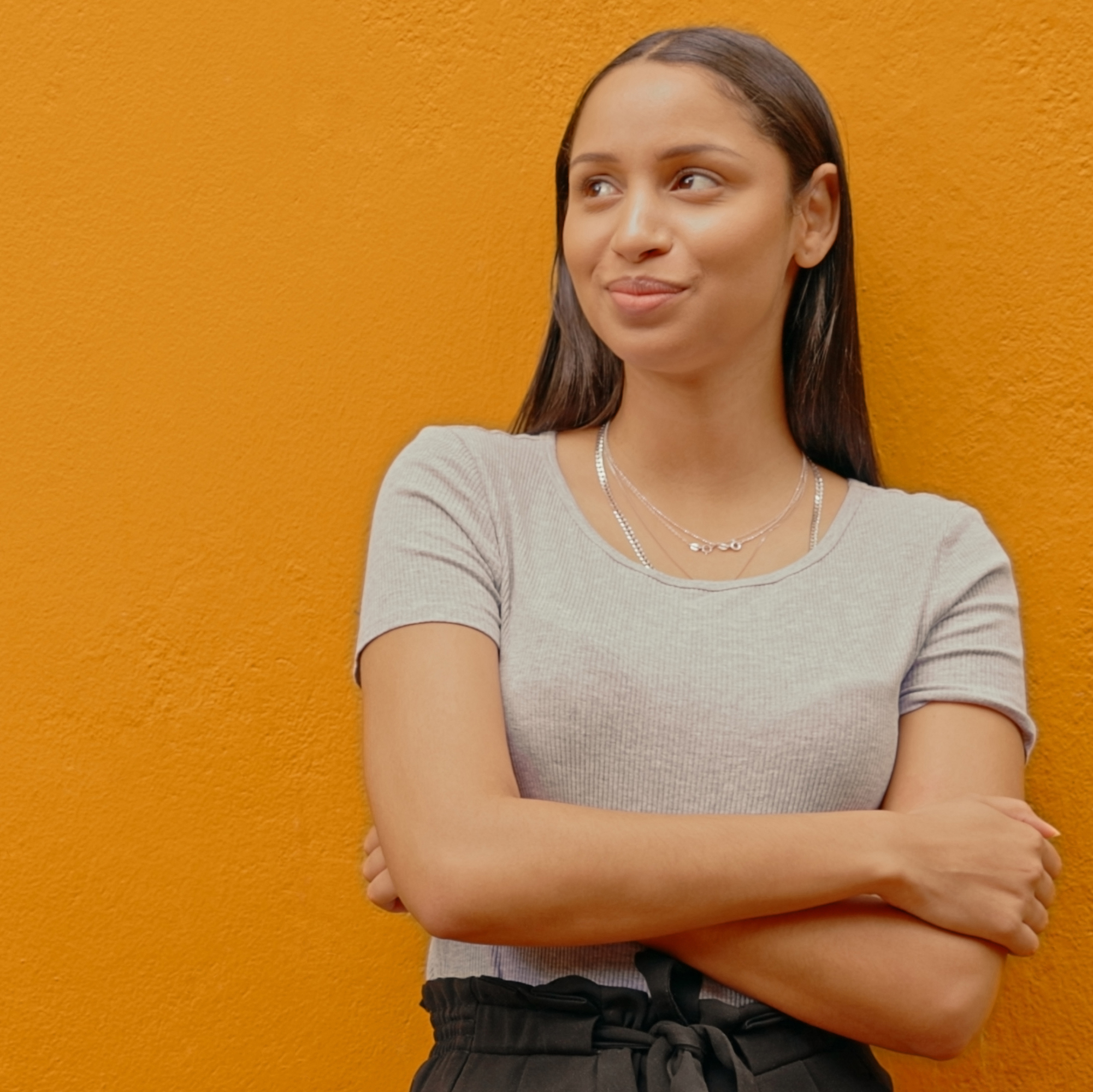 女人双臂交叉站着，目光转向别处，沉思着