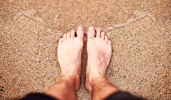 一个人双脚并拢站在海边的沙滩上。