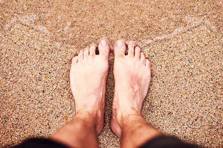 一个人双脚一起站在海边的沙滩上。