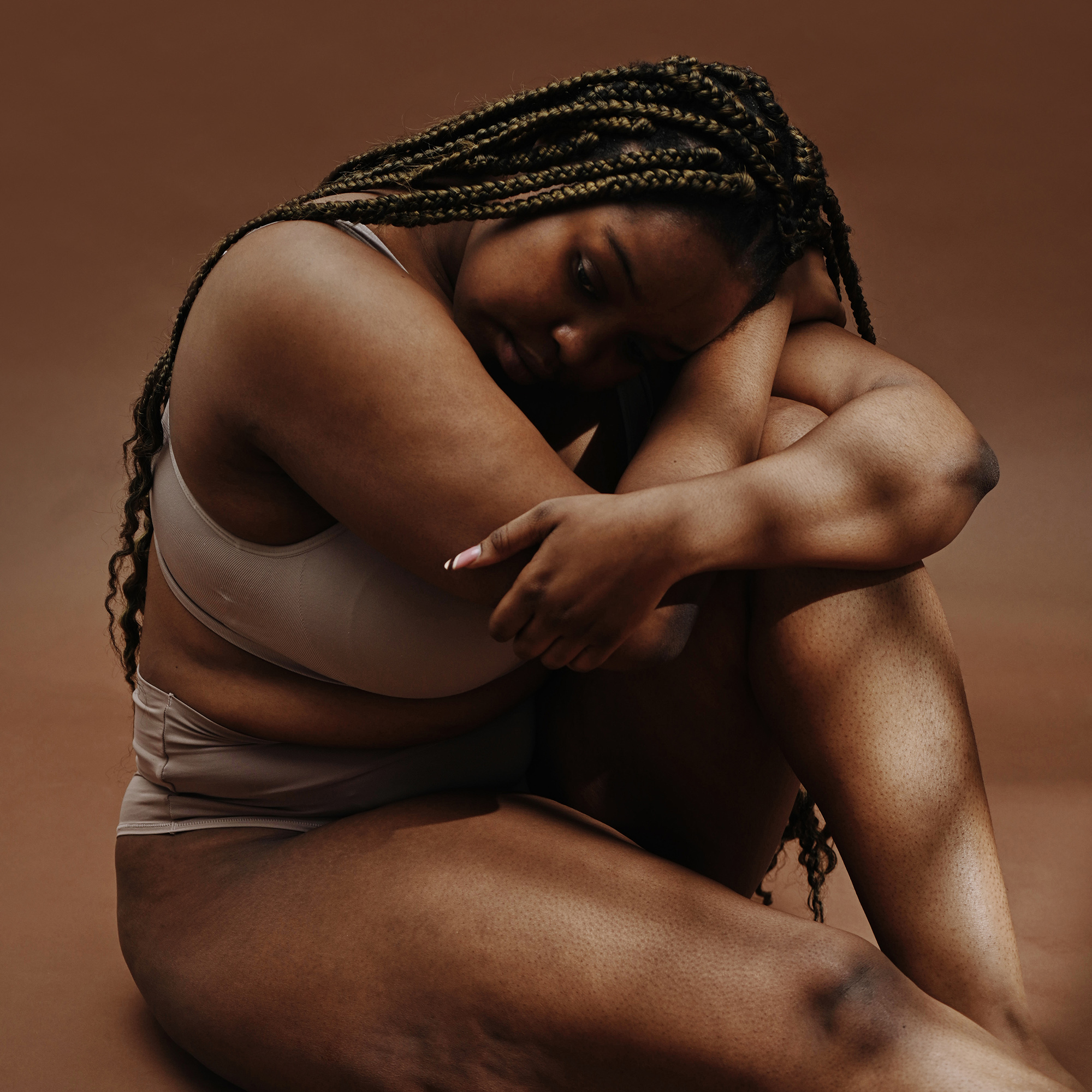 穿着内衣的胖女人坐着，看起来很悲伤