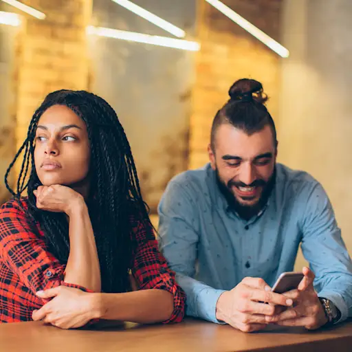 餐桌上的一对情侣。男人对着什么微笑,女人冷淡地盯着远方。