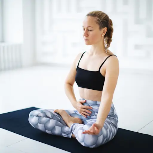 woman touching stomach while doing breathing exercise