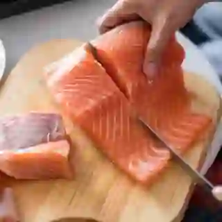 Woman's hands cutting raw salmon