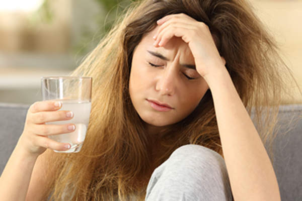 年轻女子与头痛喝一杯水。