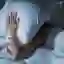 Woman in bed having difficulty sleeping and holding a pillow against her head.