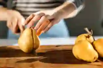Closeup of a woman cutting a pear on a cutting board.