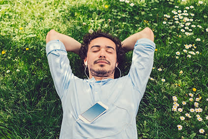 一个男人躺在草地上听音乐。