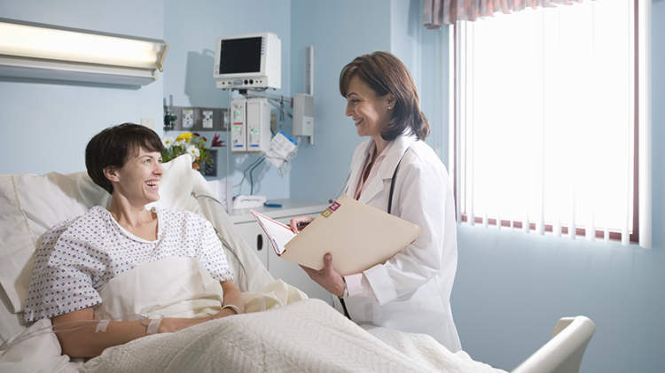 一位躺在医院病床上的妇女从她的医生那里得到了好消息。