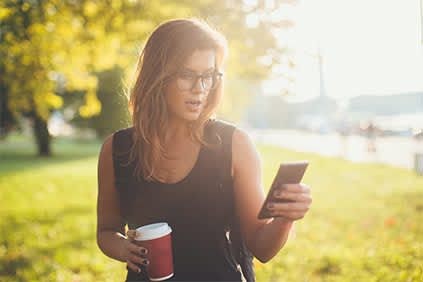 一个在公园边喝咖啡边发短信的女人。