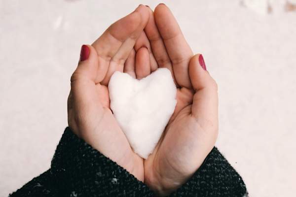 女人的手捧着心形的雪