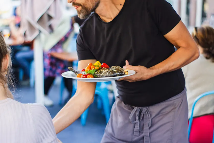 server bringing fish and vegetables to a table