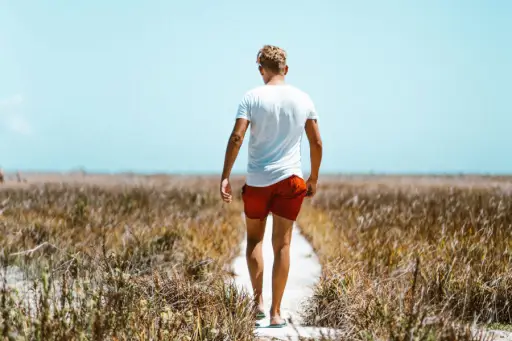 man walking to beach wearing shorts and t-shirt