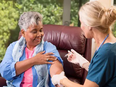 老年妇女从家庭保健专业人员那里接种带状疱疹疫苗。