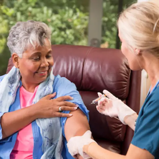 老年妇女从家庭保健专业人员那里接种带状疱疹疫苗。
