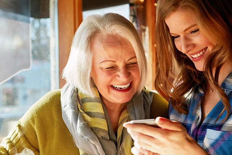 成年的女儿和年迈的母亲微笑着看着照片。