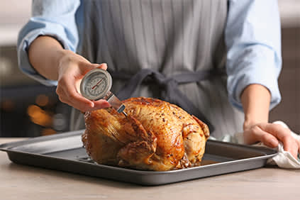 女子测量温度的烤鸡使用肉类温度计。