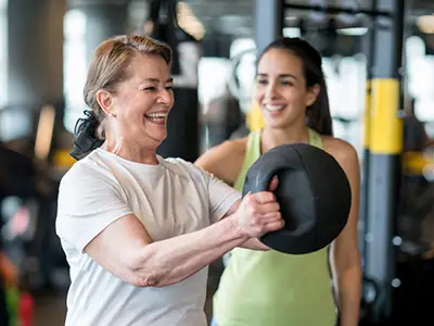 微笑的老女人和教练一起锻炼。